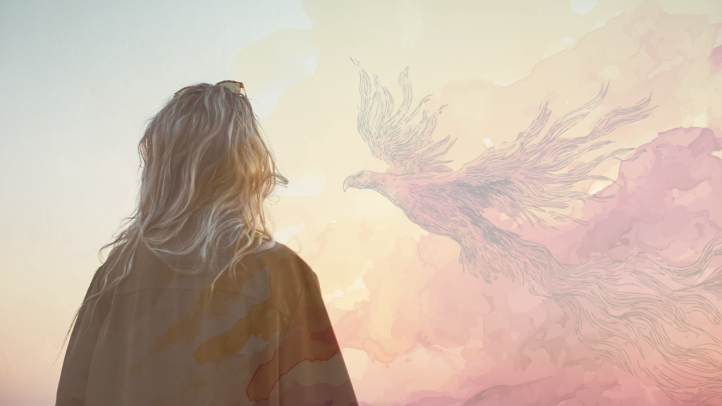 Mujer de espaldas contemplando la silueta de un fénix entre nubes en tonos terracota y rosa, símbolo de renacimiento espiritual.